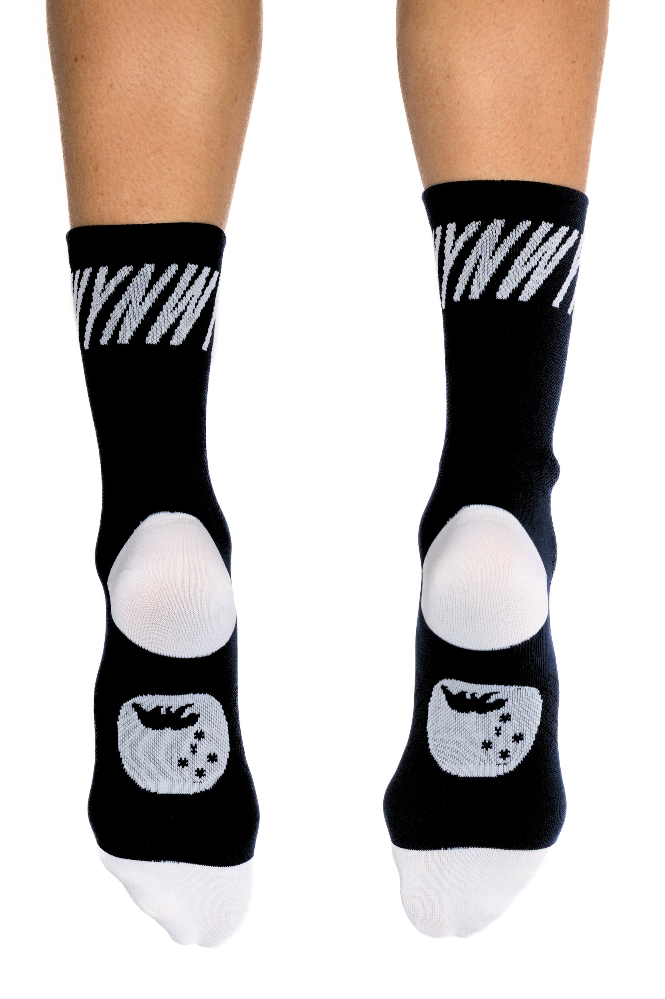Black crew socks with white graphic details, including a diagonal stripe pattern on the upper cuff and a stylized sleeping face graphic on the foot, shown on a person's feet against a white background.