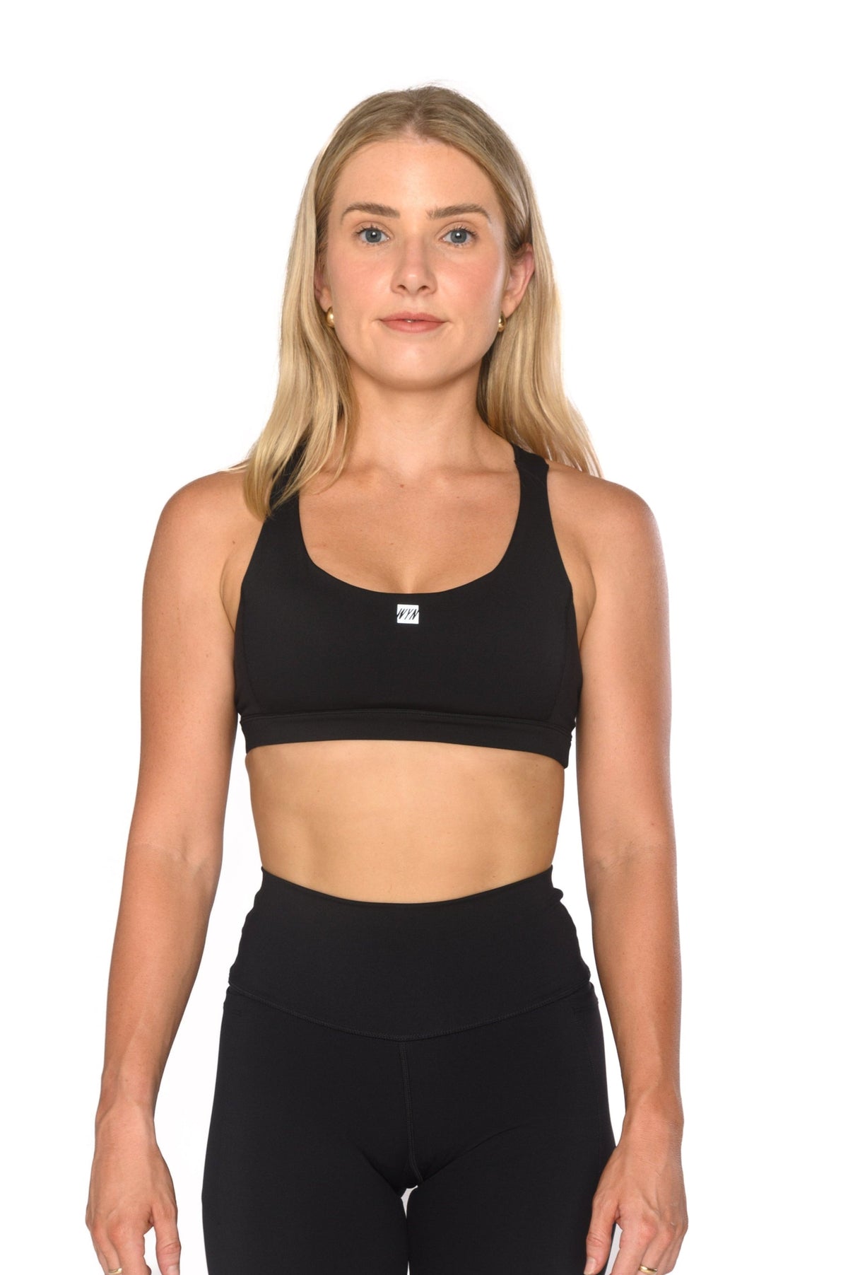 A blonde woman modeling a black athletic sports bra and matching black high-waisted leggings against a plain white background.