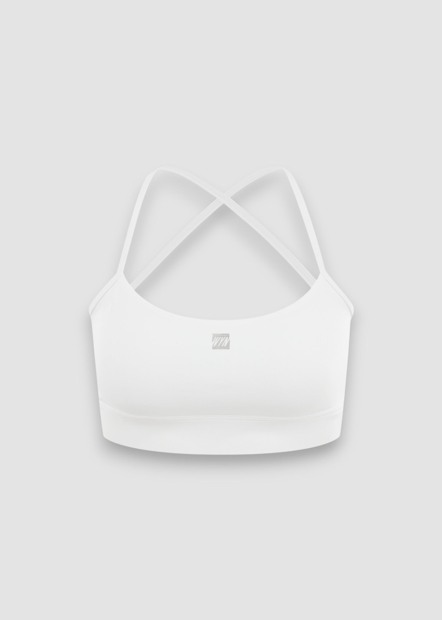 A white sports bra with thin crisscross back straps and a small square logo on the center front, displayed against a light gray background.